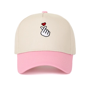 Detail of finger heart embroidery on pink and beige two-tone cotton baseball cap