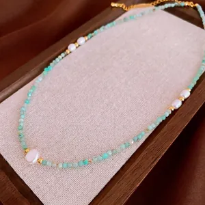 Collier élégant en amazonite plaqué or avec cinq perles sur un plateau en bois