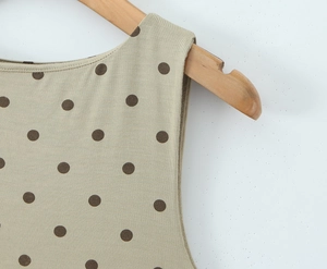 Vue détaillée de l'encolure ronde et de la texture du tissu à pois sur un cintre en bois