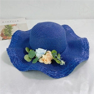 Detail of navy straw hat with wavy brim and realistic floral arrangement for beach