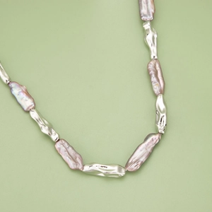 Collier de perles baroques rose violet avec maillons argentés plaqués or 18 carats sur fond vert
