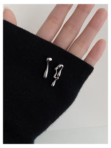 Detailed macro of silver liquid metal asymmetric geometric stud earrings on black fabric