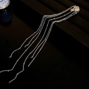 Detail of silver long chain fringe ear cuff with irregular C-shape metal design