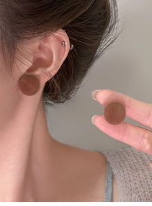 Nahaufnahme brauner beflockter Knopf-Ohrstecker an einem Model für einen Vintage-Look