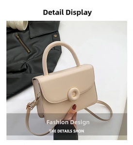 Detail showing the cream crossbody bag with round hardware, top handle and adjustable strap