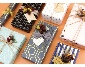 Dettaglio di carta da regalo geometrica con inserti dorati, nastri e fiori essiccati