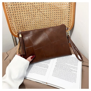Macro detail of dark brown geometric textured clutch with fringe and wrist strap