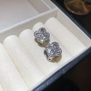 Macro shot of silver four-leaf clover earrings with sparkling pavé crystals in a jewelry box