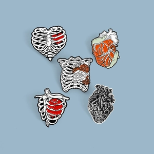 Set of 5 anatomical heart and skeleton enamel pins with floral details on light background