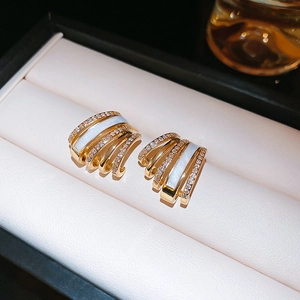 Macro detail of gold-plated multi-layer C-shaped earrings with shell and zircon inlay
