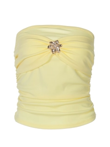 Detalle de top palabra de honor amarillo claro con tela plisada y hebilla floral dorada