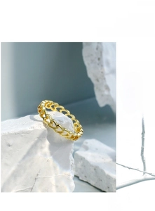 Artistic close-up of gold hollow heart ring on white textured stone with branch