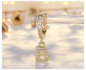 Detailed macro view of S925 silver hoop earring with paved white zircon letter B pendant