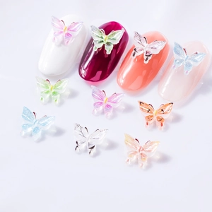 3D butterfly nail art charms with glitter finish on diverse colored false nail tips