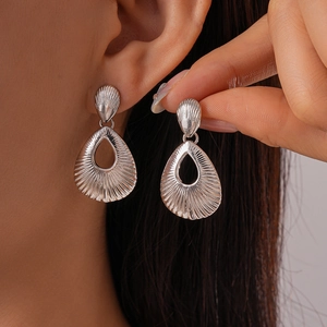 Silver hollow teardrop earrings with shell texture shown on model for a chic look