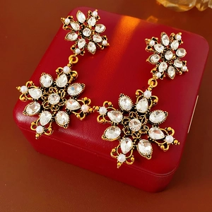 Gros plan de boucles d'oreilles vintage dorées avec cristaux et perles sur écrin rouge
