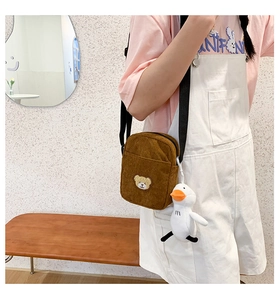 Brown corduroy crossbody bag with cute bear patch and plush duck charm on a model