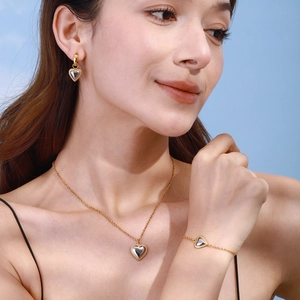 Close-up of golden stainless steel heart jewelry set on a model against blue sky