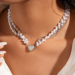 Détail d'un collier multicouche avec perles d'imitation et pendentif coeur en strass sur modèle