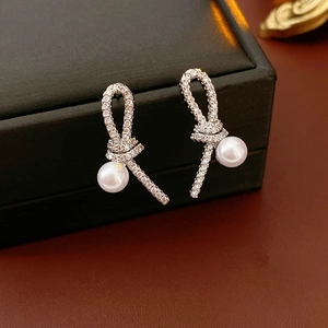 Détail de boucles d'oreilles nœuds argentés avec zircons et perles sur un écrin noir