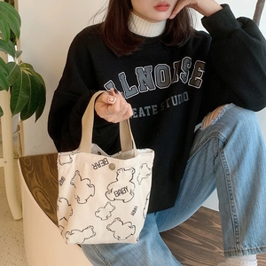 Detailed texture of off-white corduroy tote bag featuring a black bear and baby bear text