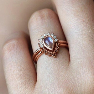 Macro detail of rose gold pear-shaped moonstone ring with intricate filigree and small diamonds