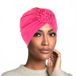 Pink braided turban hat for women with twisted floral design on white background