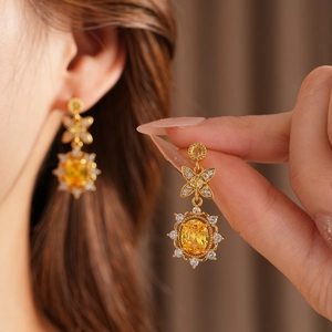Detailansicht goldener Vintage-Ohrringe mit gelbem Edelstein und Zirkonia-Schleifendesign