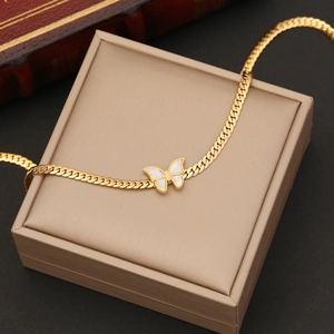 Gold blade chain necklace with a white mother-of-pearl butterfly pendant on jewelry box