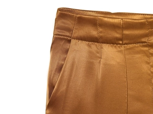 Detail of high-waist bronze satin wide-leg trousers showing smooth fabric texture and pockets