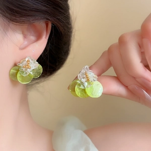 Macro view of delicate shell flower earrings with green petals and gold bead accents