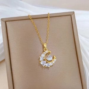 Macro detail of a golden crescent moon necklace with zircon heart inlay on silk background