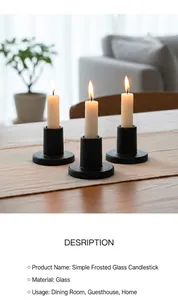 Three matte black glass candle holders on a wooden table with warm ambient lighting