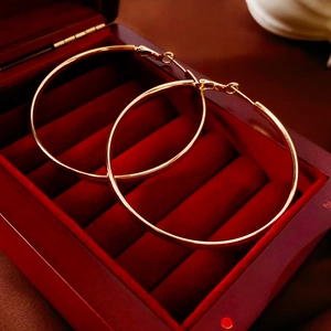 Gros plan de grandes créoles dorées présentées dans un écrin à bijoux en velours rouge