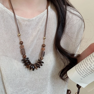 Close-up of bohemian wooden bead pendant necklace with rustic brown geometric charms
