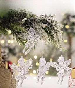 Detailed view of clear acrylic angel ornaments with musical instruments on snowy pine branch
