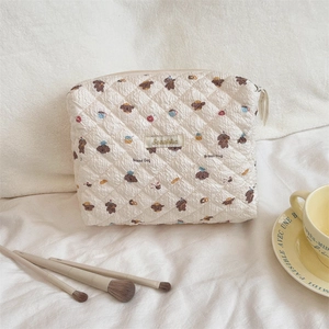 Detailed close-up of quilted cosmetic bag with cute bread dog pattern and makeup brushes