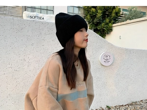 Outdoor shot of a woman wearing a thick black double-layer knit rabbit fur beanie hat