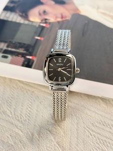 Close-up of minimalist silver square watch with black dial and woven mesh steel strap