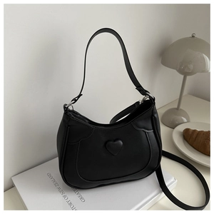 Detail of a black crescent shoulder bag featuring a padded heart and smooth faux leather