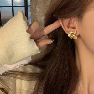 Close-up of elegant gold flower stud earrings with white pearl drop on female model