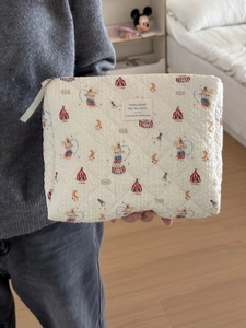 Detail of quilted beige toiletry bag with colorful circus patterns and soft texture