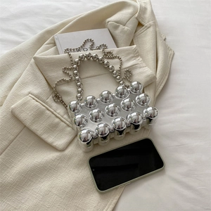Silver metallic egg shell evening bag with bubble texture and chain strap on beige blazer