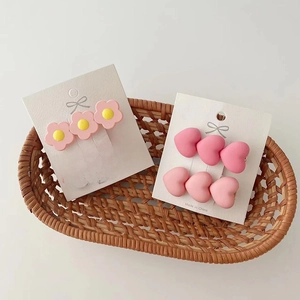 Close-up of pink resin flower and heart hair clips set in a rustic woven basket