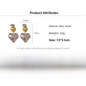 Detailed view of large heart earrings in gold and silver finish with 7.5x3.5cm dimensions