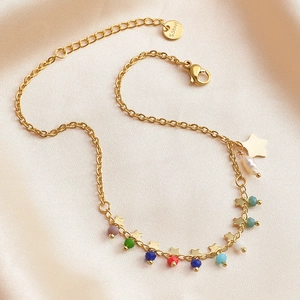 Macro detail of gold stainless steel anklet with colorful beads and star pendant on silk