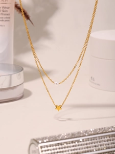 Macro shot of double-layered gold chain with a white pearl and star pendant charm