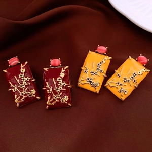 Macro detail of vintage oil-dripped square earrings with golden plum blossom relief