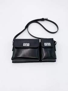 Detail of black double-pouch baguette bag with silver rotating lock and leather texture