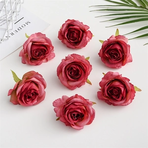 Detailed top view of seven dark pink artificial silk rose heads on white surface
